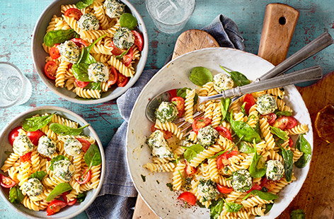 Make this colourful Caprese pasta salad for a fresh summer lunch. Creamy balls of garlic & herbs cheese are rolled in basil and lemon zest, then tossed through pasta with spinach, tomatoes and an easy olive oil dressing for a quick 30 min meal.